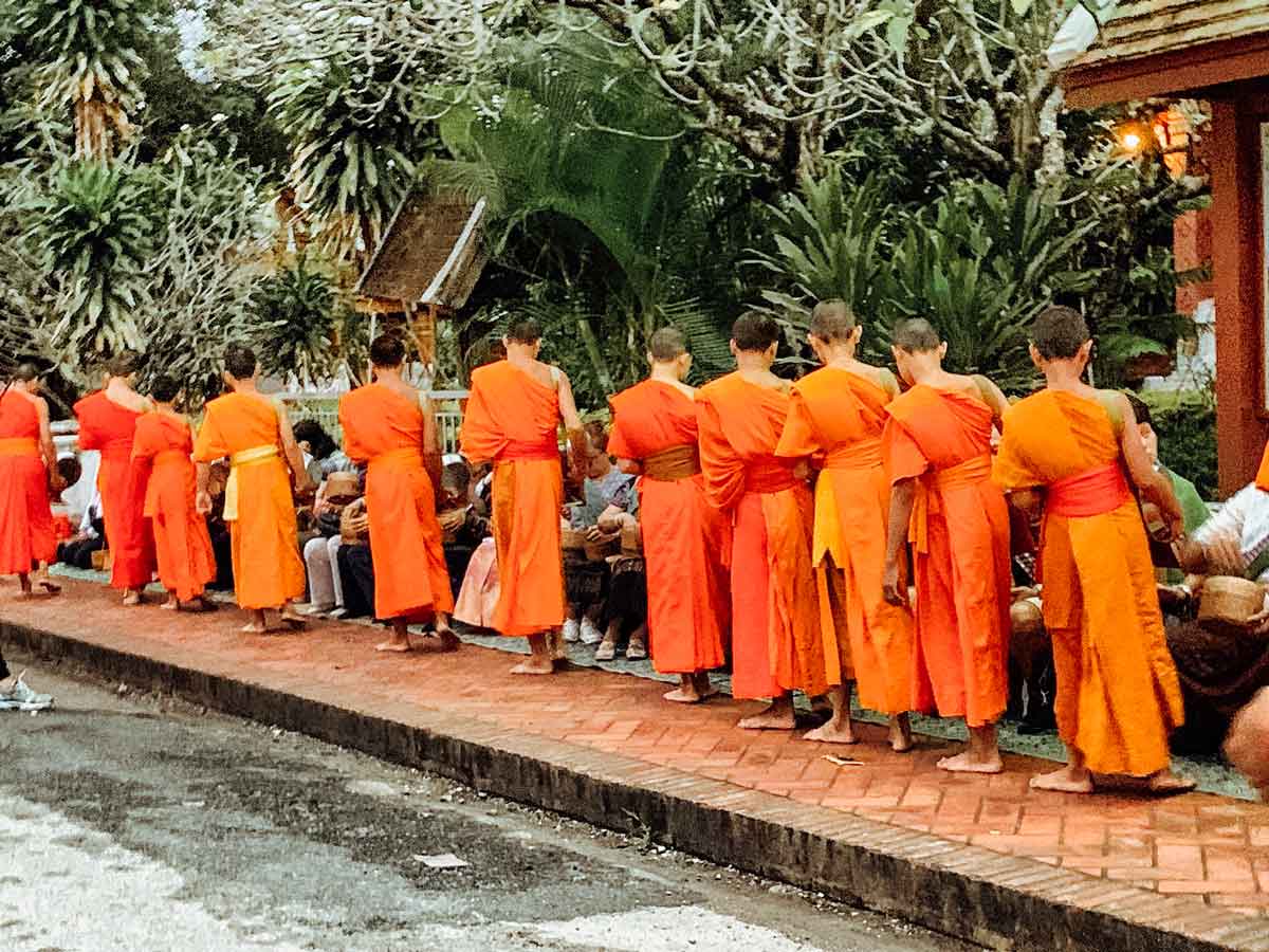 Monks walking near people in Luang Prabang, Laos