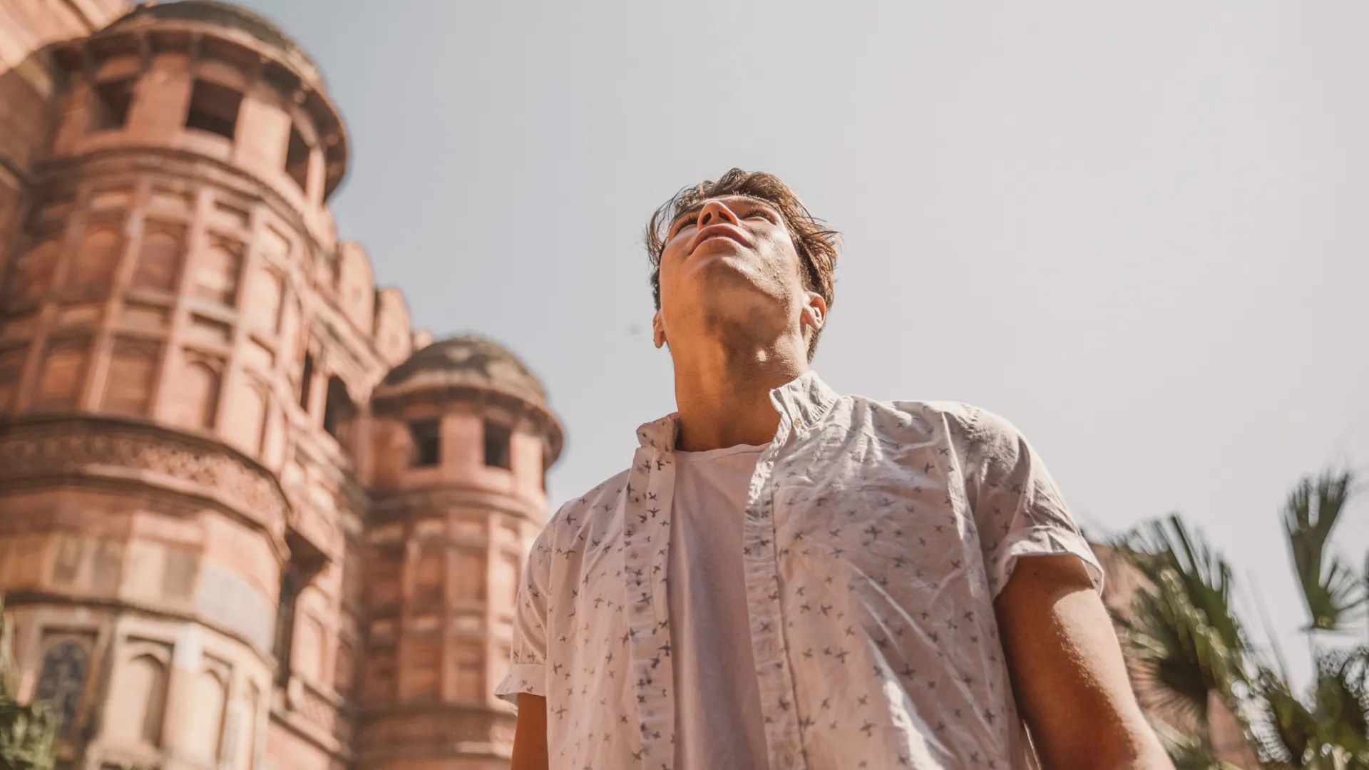 Man in pattern button-up looking up at historic fortress, Agra, India