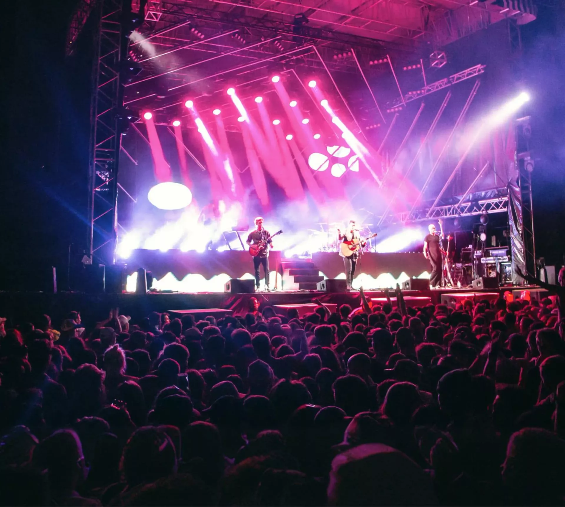Live band performing on stage with dramatic pink and purple lighting to a large crowd at Rhythm and Alps music festival in New Zealand - Contiki NZ Festival Tour