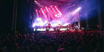 Live band performing on stage with dramatic pink and purple lighting to a large crowd at Rhythm and Alps music festival in New Zealand - Contiki NZ Festival Tour