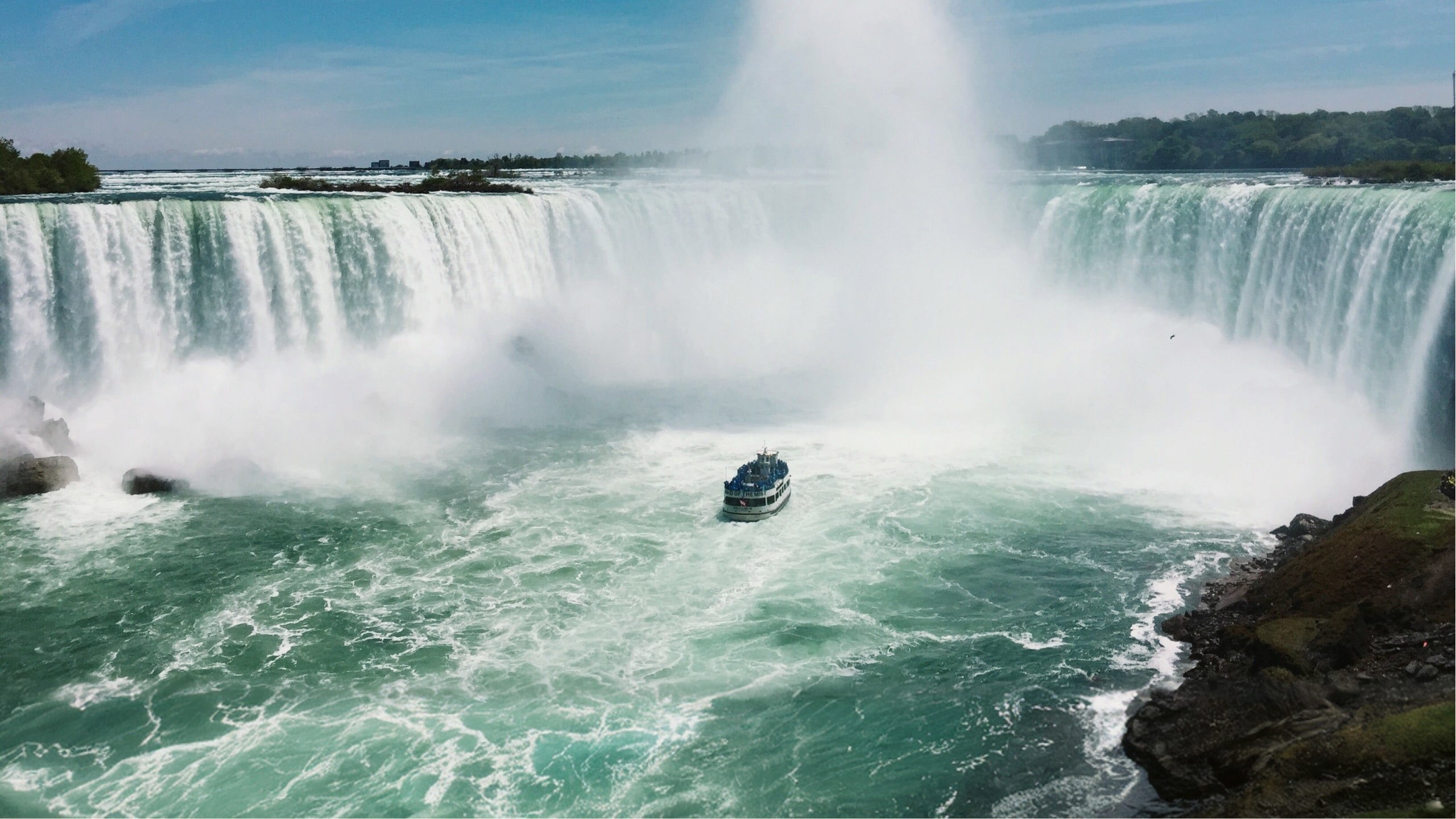 Boat sails through the mist beneath Niagara Falls on Contiki's Canada: Toronto, Niagara & Quebec Tour, experiencing one of Canada's most iconic natural wonders