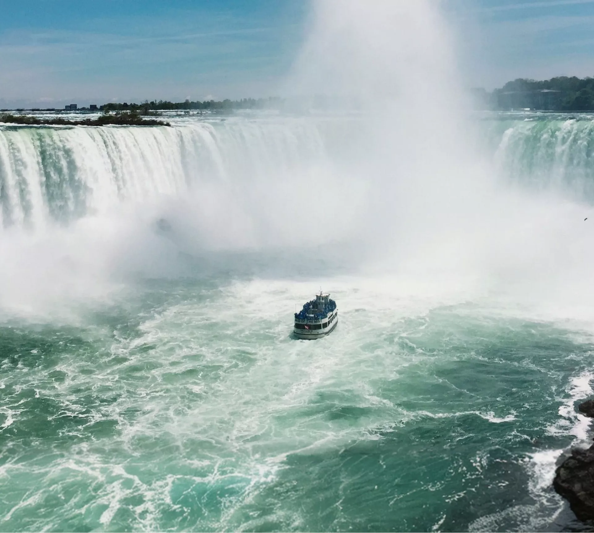 Boat sails through the mist beneath Niagara Falls on Contiki's Canada: Toronto, Niagara & Quebec Tour, experiencing one of Canada's most iconic natural wonders