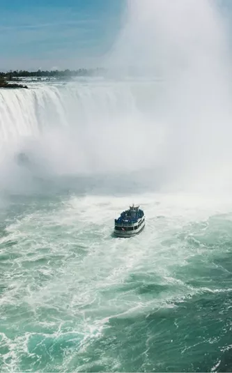 Boat sails through the mist beneath Niagara Falls on Contiki's Canada: Toronto, Niagara & Quebec Tour, experiencing one of Canada's most iconic natural wonders