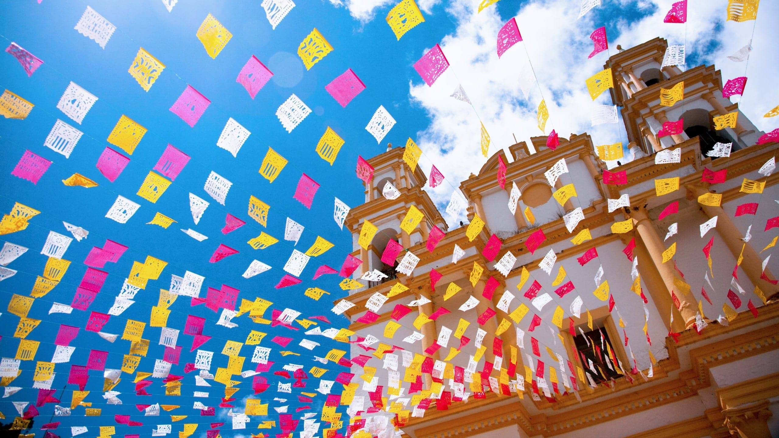 Colourful papel picado flutter above the Metropolitan Cathedral in Mexico City on Contiki's Mexico City to Antigua Tour