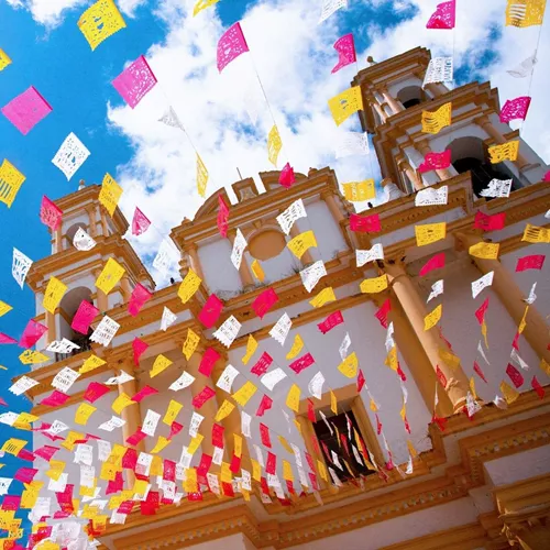 Colourful papel picado flutter above the Metropolitan Cathedral in Mexico City on Contiki's Mexico City to Antigua Tour