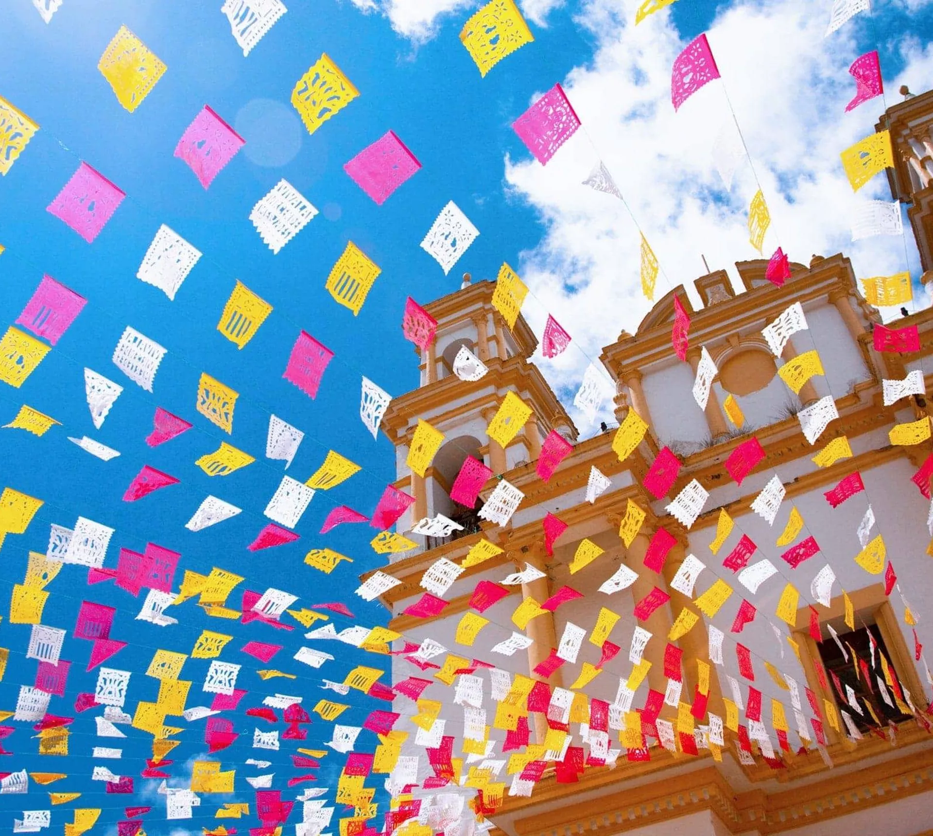 Colourful papel picado flutter above the Metropolitan Cathedral in Mexico City on Contiki's Mexico City to Antigua Tour