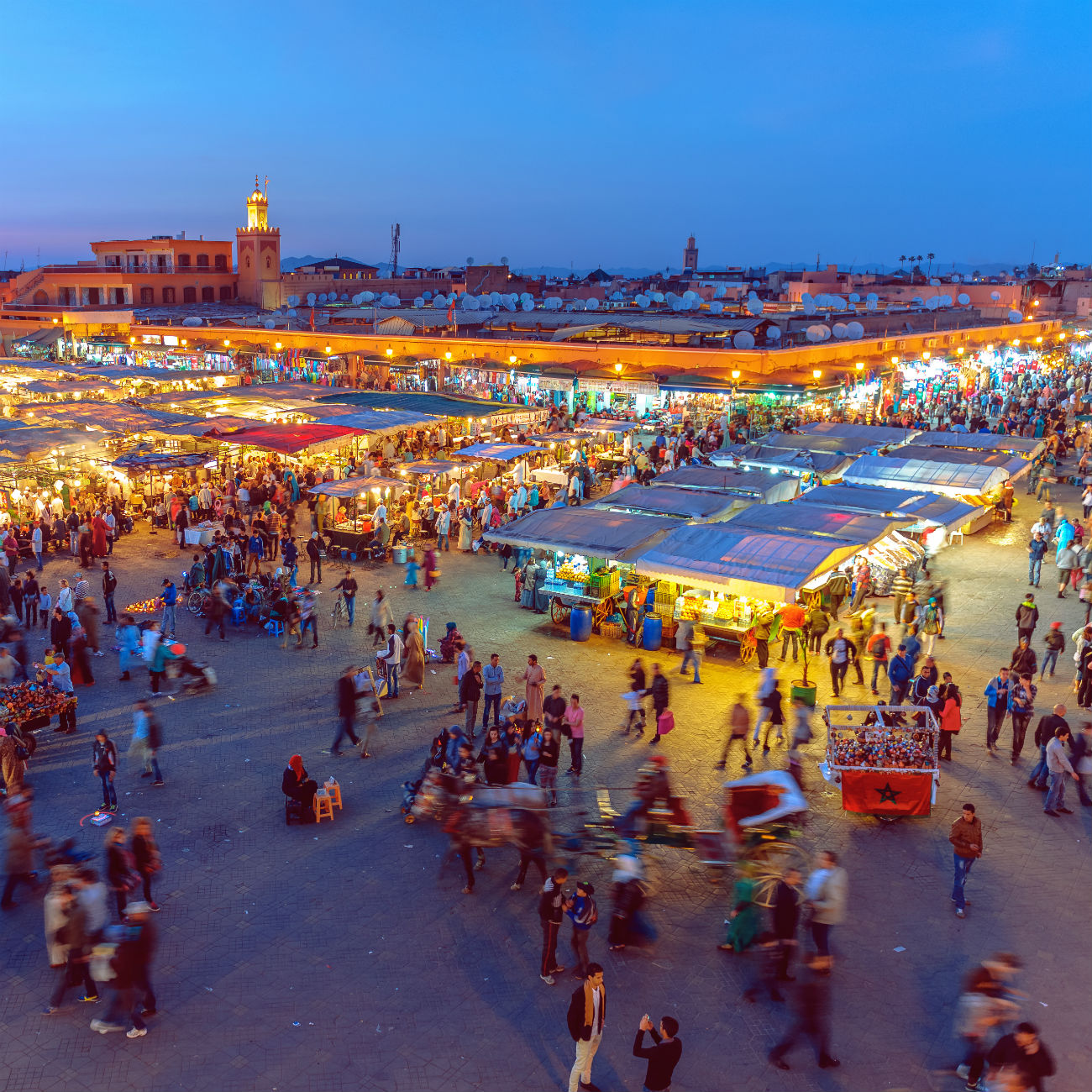 A crowd of people walking around a souk or market at night in Morocco