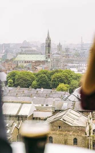 Traveller drinking a pint of Guinness at the Guinness Storehouse rooftop bar overlooking the Dublin city skyline - Contiki St Patrick's Day Festival Tour Ireland