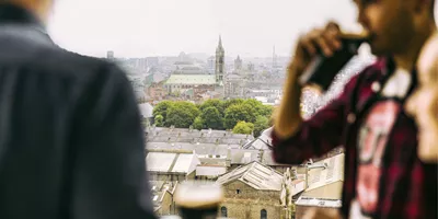 Traveller drinking a pint of Guinness at the Guinness Storehouse rooftop bar overlooking the Dublin city skyline - Contiki St Patrick's Day Festival Tour Ireland