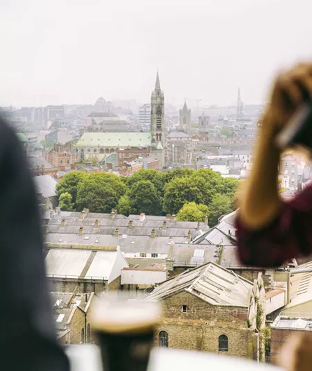 Traveller drinking a pint of Guinness at the Guinness Storehouse rooftop bar overlooking the Dublin city skyline - Contiki St Patrick's Day Festival Tour Ireland
