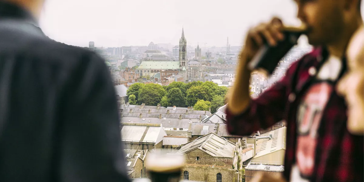 Traveller drinking a pint of Guinness at the Guinness Storehouse rooftop bar overlooking the Dublin city skyline - Contiki St Patrick's Day Festival Tour Ireland