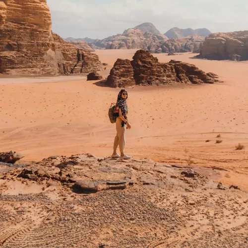 Female traveller on a sandstone rock overlooking the dramatic desert landscape of Wadi Rum Valley of the Moon Jordan - Contiki Jordan Tour