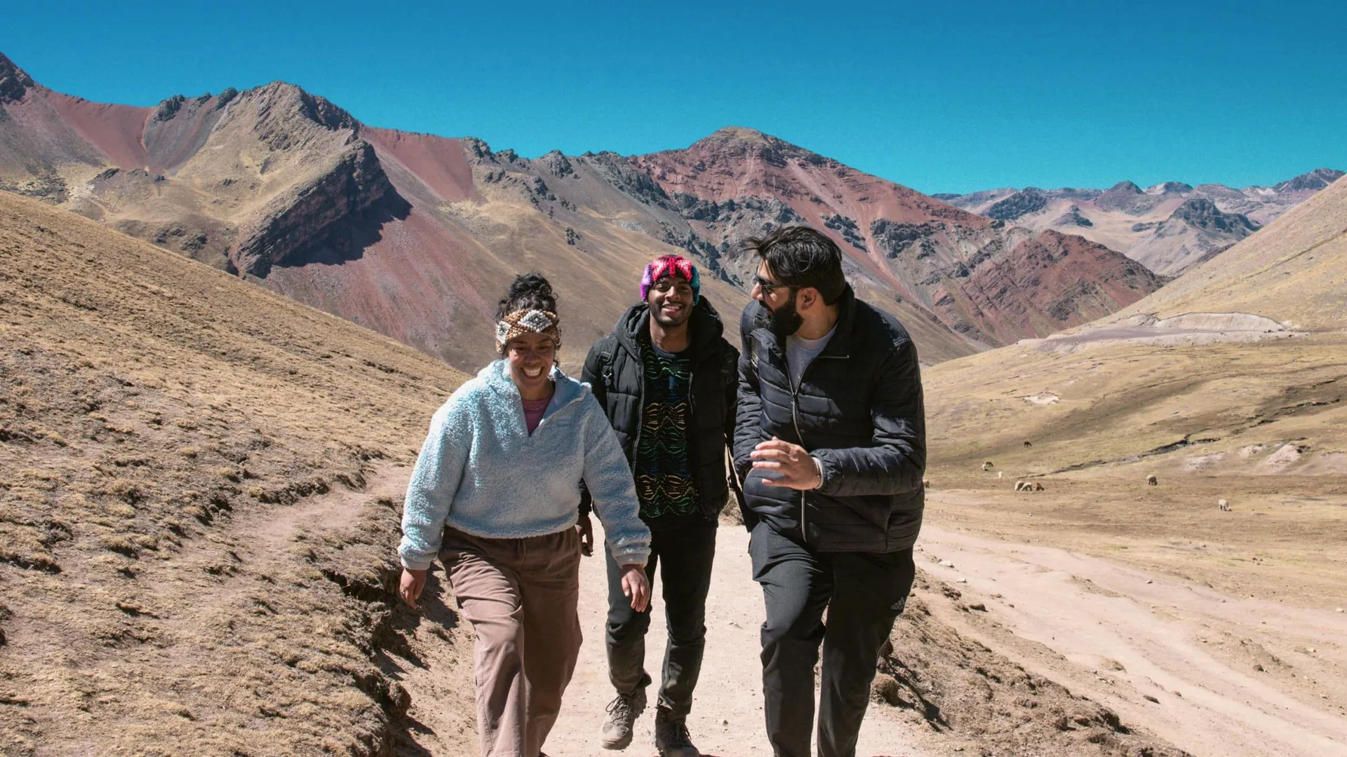 Contiki travellers hiking through the colourful Andes Mountains near Rainbow Mountain, Peru, surrounded by dramatic alpine scenery on the Ultimate South America Tour