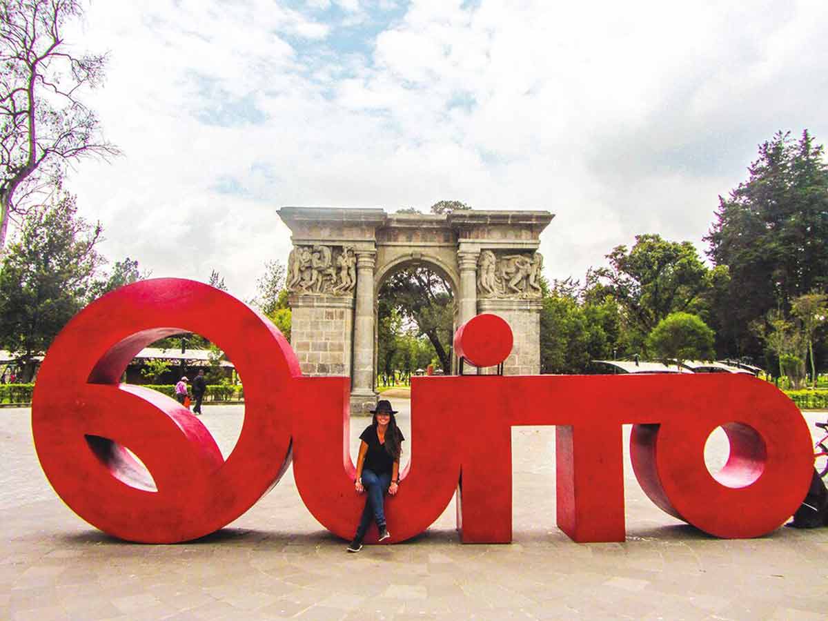 Woman Sitting On A Large Quito Sign