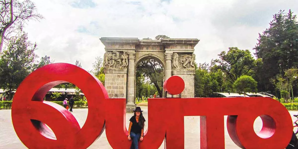 Woman Sitting On A Large Quito Sign