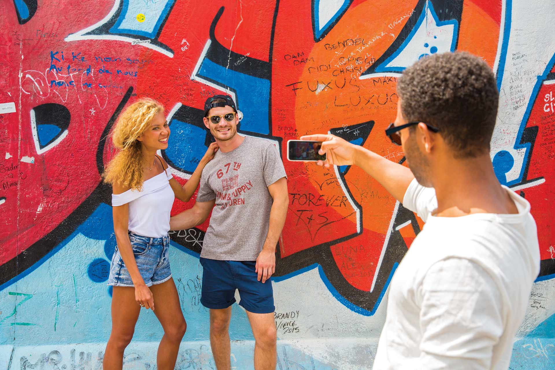 People taking a photo in front of a graffiti wall