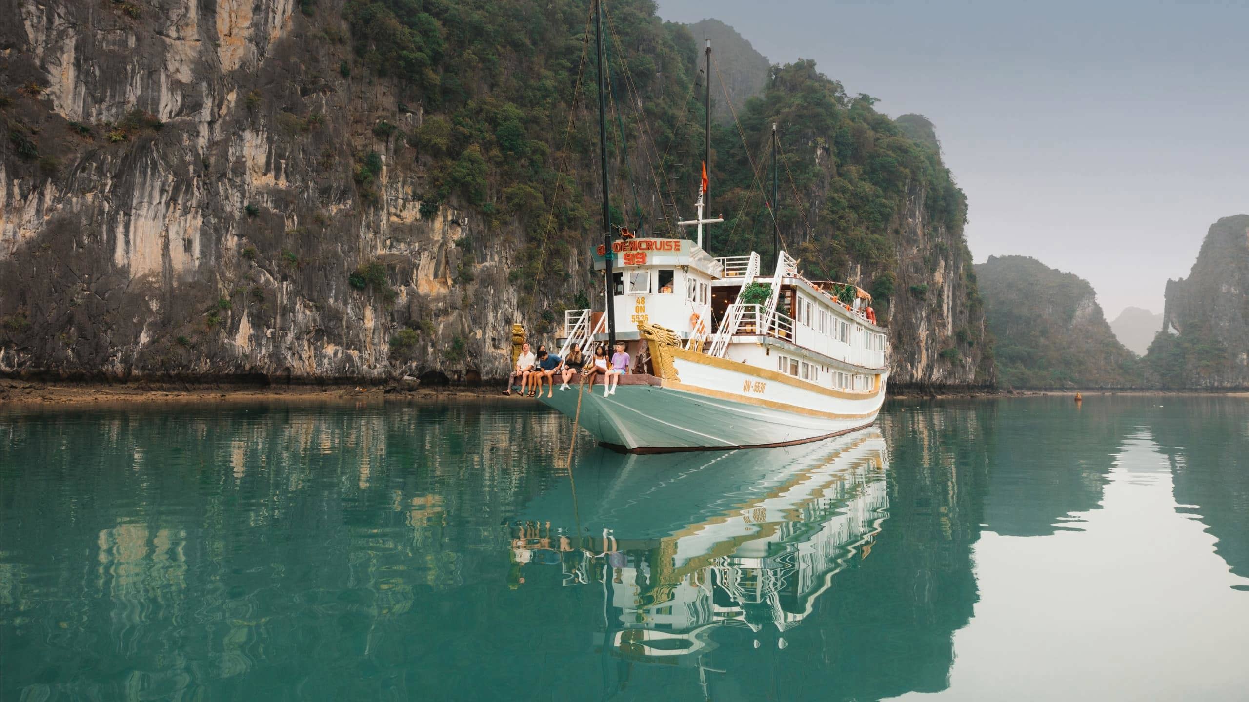 Contiki travellers relaxing aboard an overnight cruise through Ha Long Bay, Vietnam, surrounded by towering limestone karsts on the Ultimate South East Asia Tour