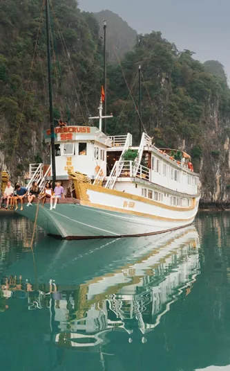 Contiki travellers relaxing aboard an overnight cruise through Ha Long Bay, Vietnam, surrounded by towering limestone karsts on the Ultimate South East Asia Tour