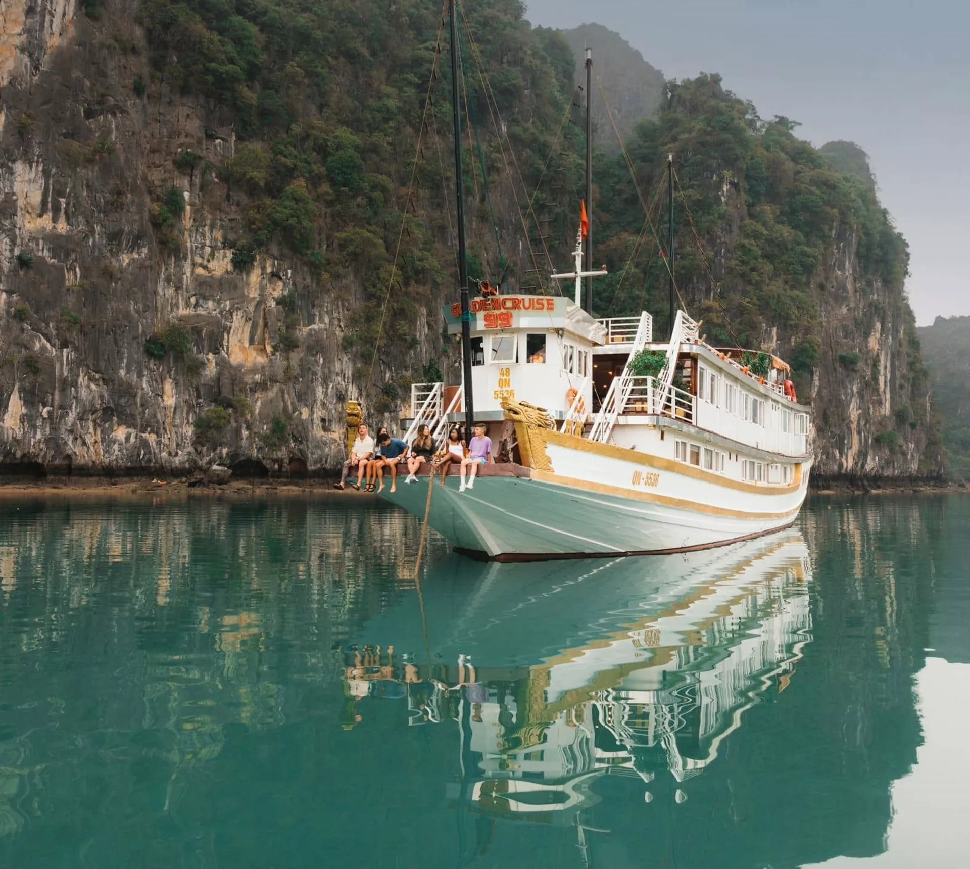 Contiki travellers relaxing aboard an overnight cruise through Ha Long Bay, Vietnam, surrounded by towering limestone karsts on the Ultimate South East Asia Tour