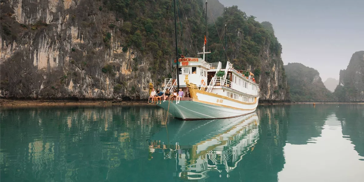 Contiki travellers relaxing aboard an overnight cruise through Ha Long Bay, Vietnam, surrounded by towering limestone karsts on the Ultimate South East Asia Tour