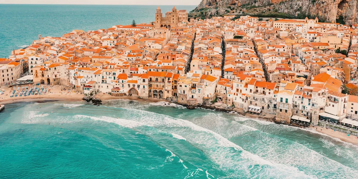 Aerial view of Cefalù's historic coastline and sandy beach in Sicily on the Contiki Best of Italy with Sicily Tour
