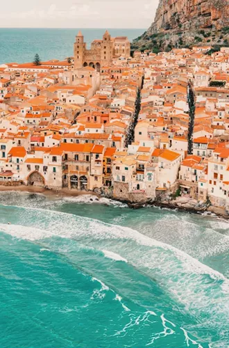 Aerial view of Cefalù's historic coastline and sandy beach in Sicily on the Contiki Best of Italy with Sicily Tour