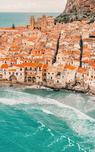 Aerial view of Cefalù's historic coastline and sandy beach in Sicily on the Contiki Best of Italy with Sicily Tour