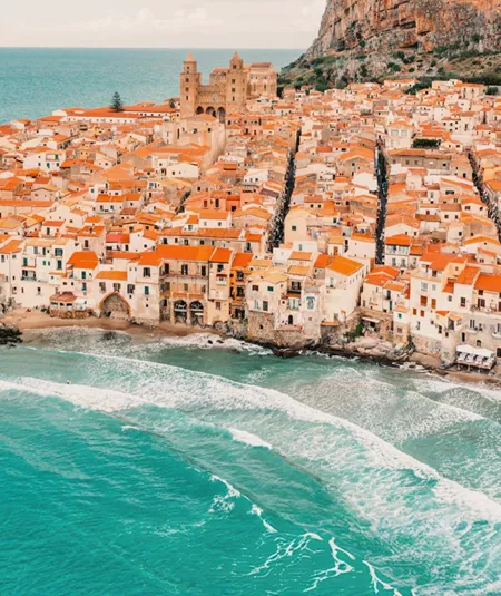 Aerial view of Cefalù's historic coastline and sandy beach in Sicily on the Contiki Best of Italy with Sicily Tour