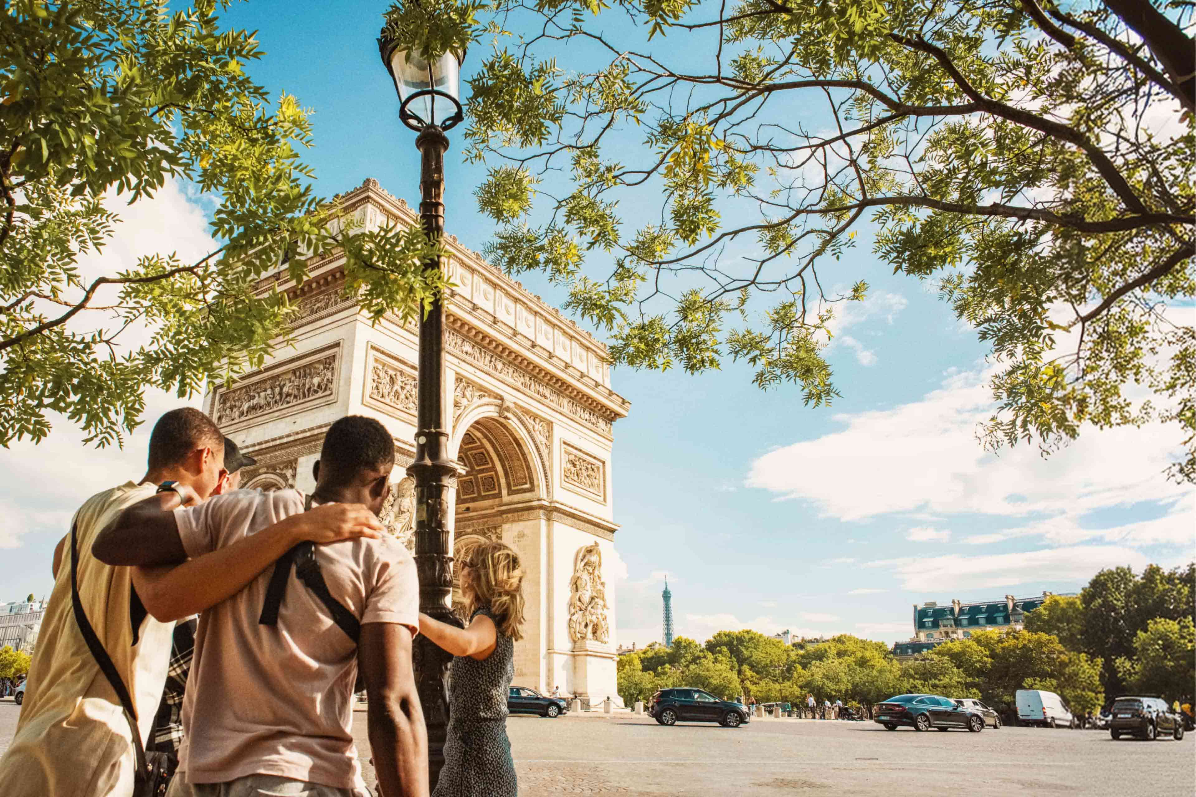 Group of travellers taking in the Arc de Triomphe with the Eiffel Tower visible in the distance, Paris, France.