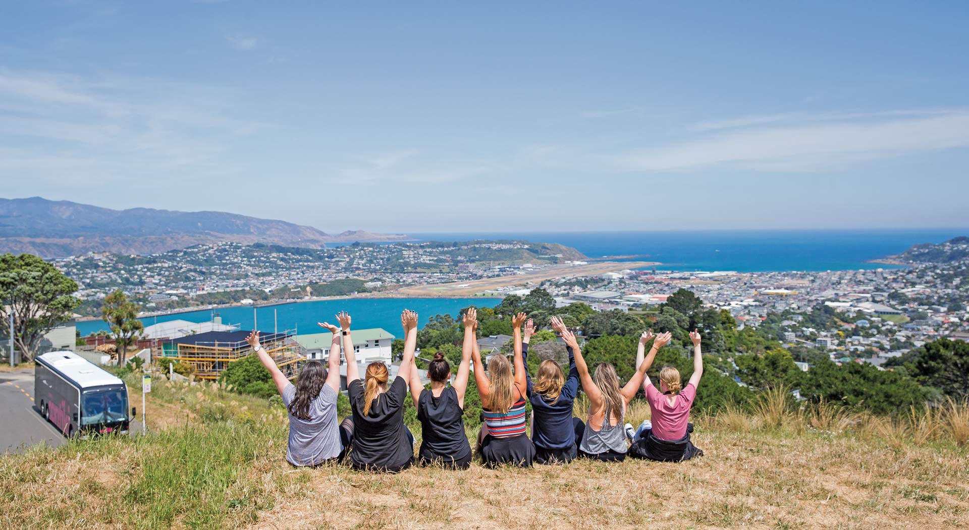 Tourists sitting on a hill with view on Wellington in New Zealand