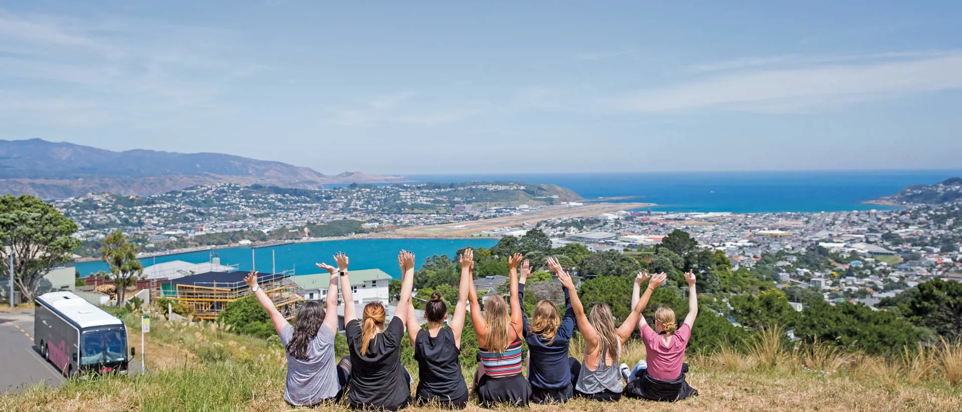 Tourists sitting on a hill with view on Wellington in New Zealand