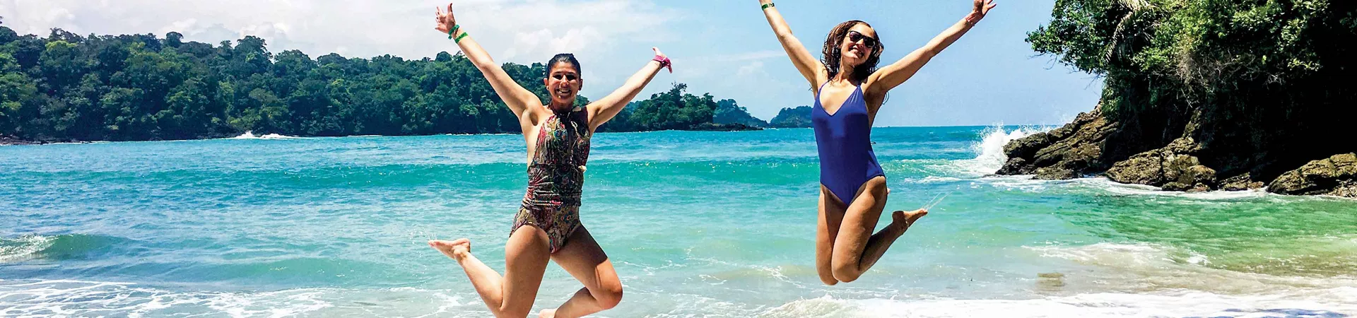 Two Female Travelers Jumping On Beach In Costa Rica