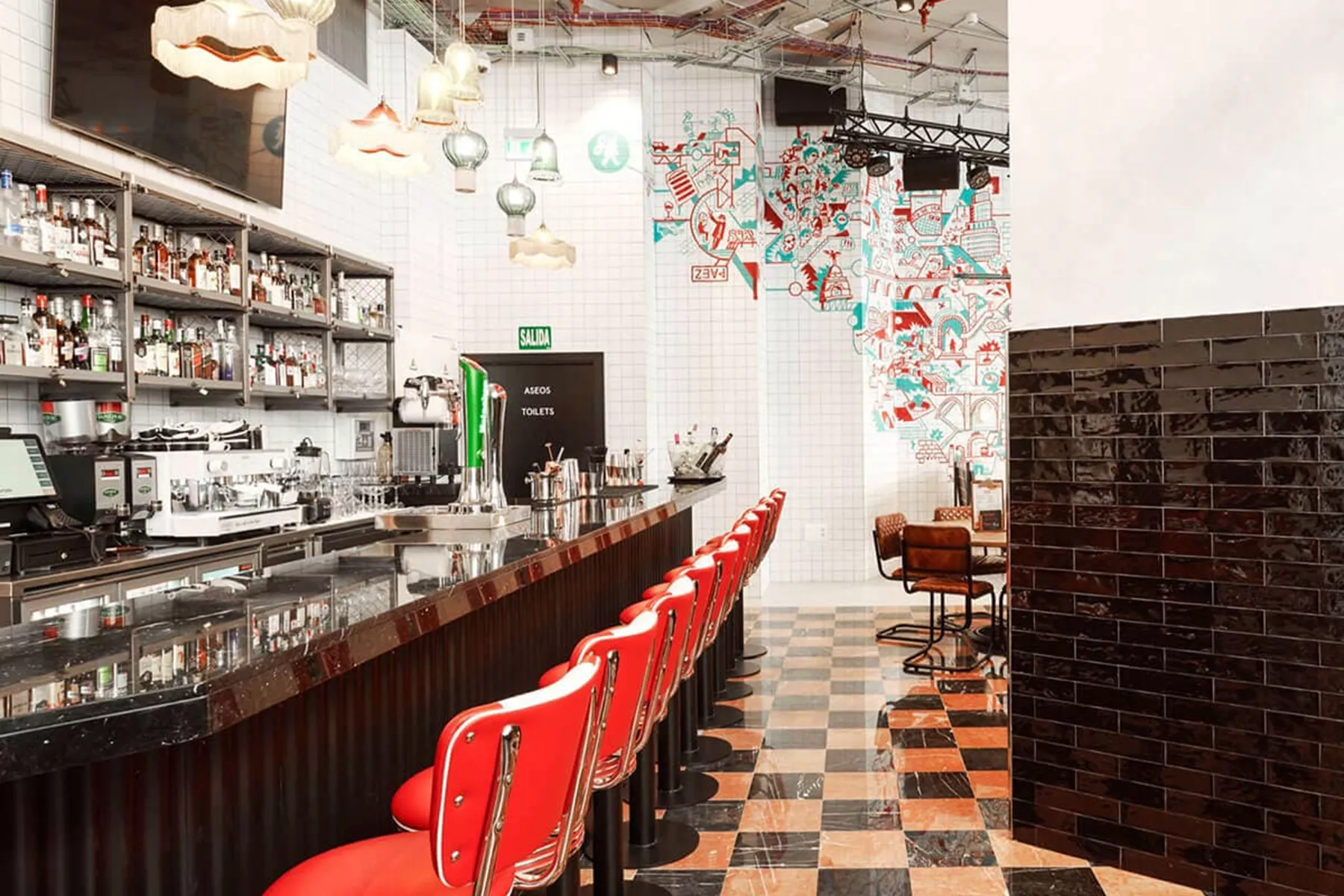 Generator Hostel bar with row of red chairs and mosaic wall in the background 