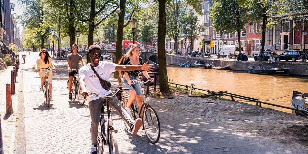 People On Bikes In Amsterdam Cycling Along Canal