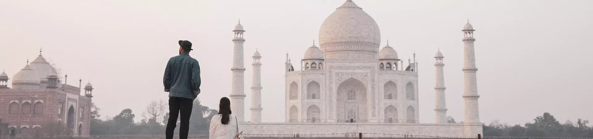 A couple sitting on a wall outside Taj Mahal