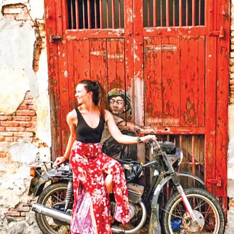 A woman in a dress posing for a photo on a motorcycle