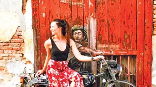 A woman in a dress posing for a photo on a motorcycle