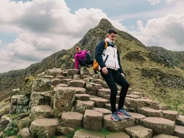 Travellers explore the Giant's Causeway, with its iconic basalt columns and dramatic coastal landscape, on the Contiki Best of Great Britain & Ireland Tour