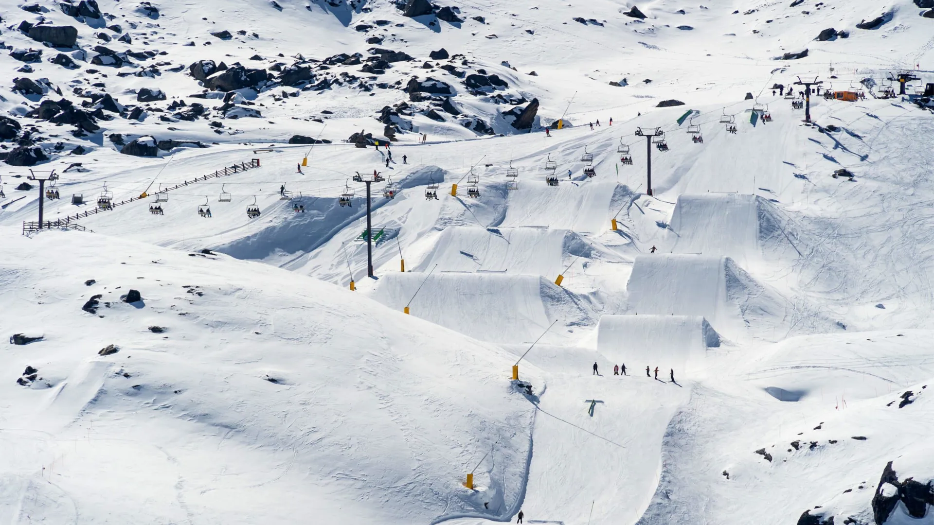 Aerial view of skiers and snowboarders on the ski runs with chairlifts and snow jumps n New Zealand - Contiki Ski NZ Tour