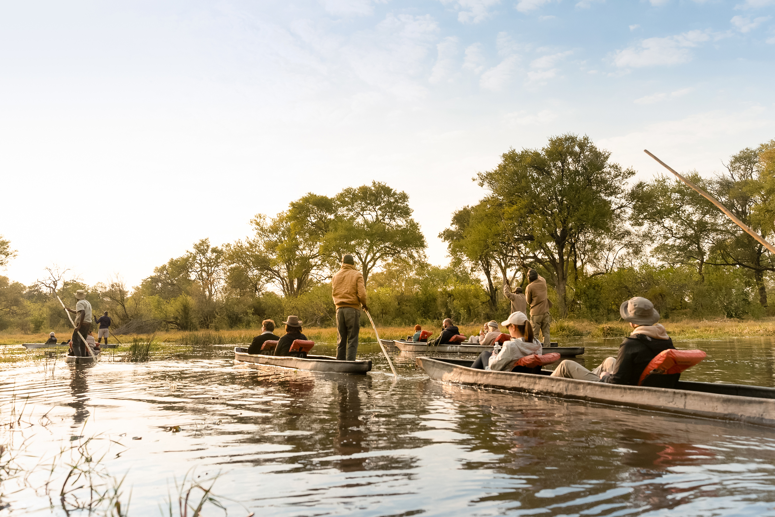 Travelers with locals on traditional boats at the Okavango Delta in Botswana