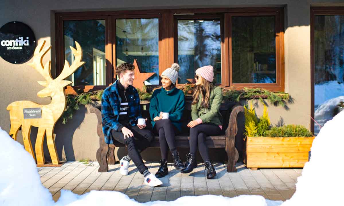 Young Travelers Sitting Bench In Snow Austria