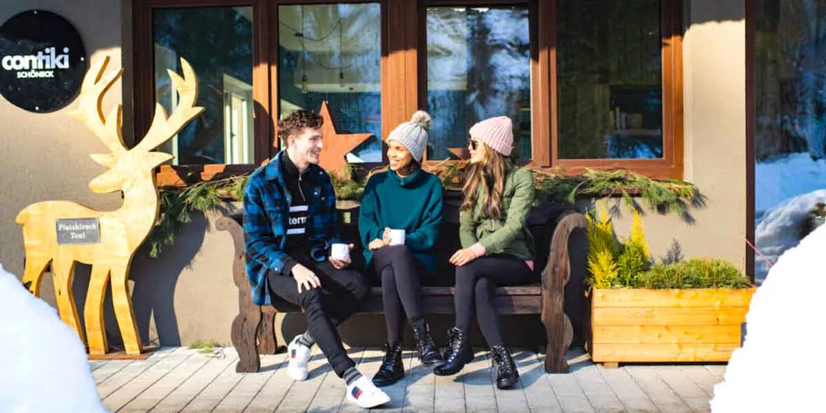 Young Travelers Sitting Bench In Snow Austria