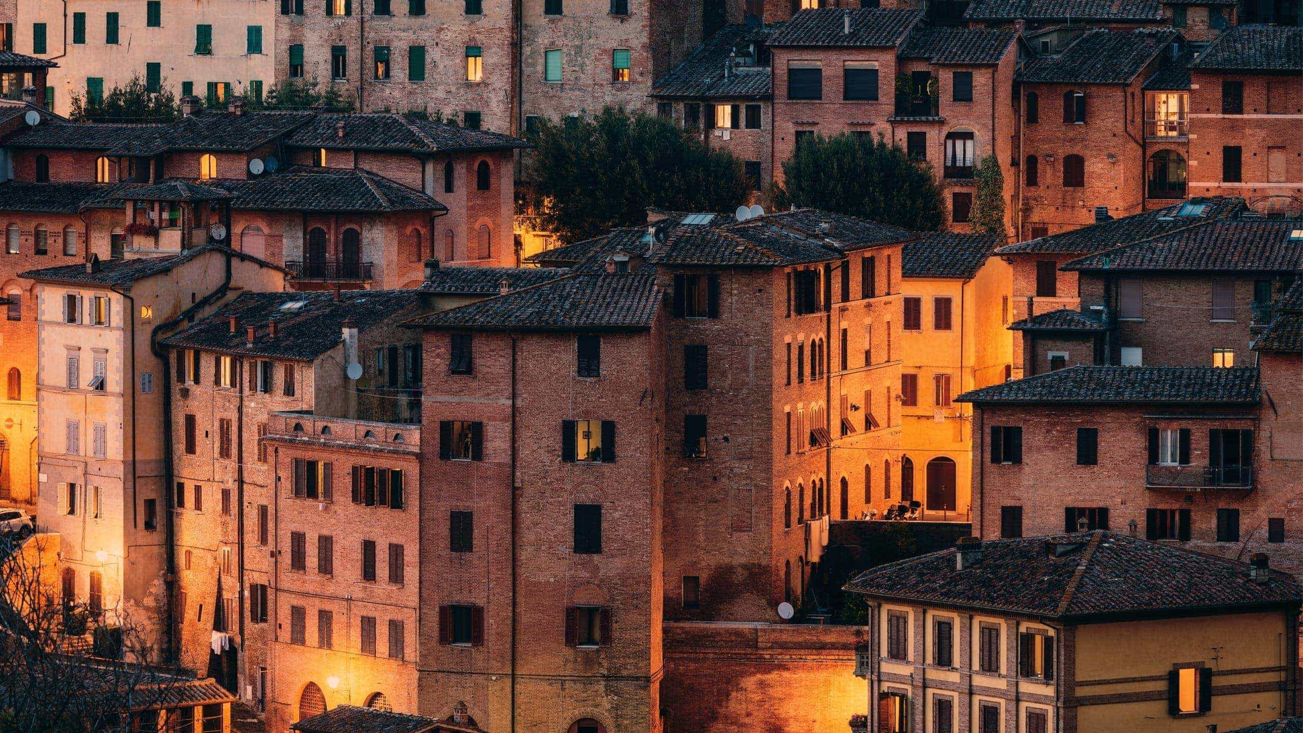 Historic Tuscan town at sunset, featuring terracotta rooftops and traditional Italian architecture on the Contikii Tuscan Escape Tour
