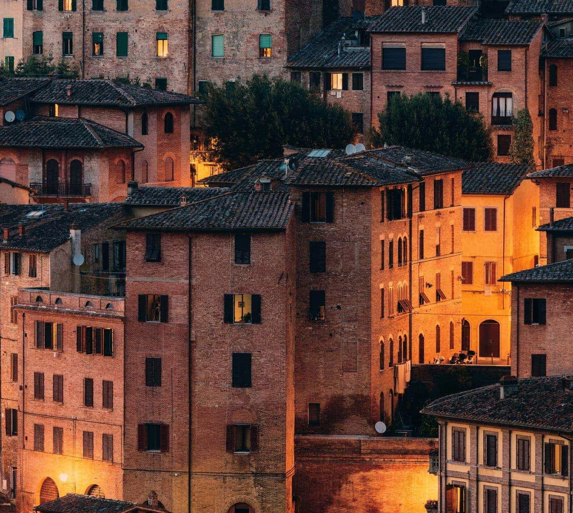 Historic Tuscan town at sunset, featuring terracotta rooftops and traditional Italian architecture on the Contikii Tuscan Escape Tour