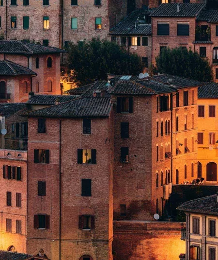 Historic Tuscan town at sunset, featuring terracotta rooftops and traditional Italian architecture on the Contikii Tuscan Escape Tour