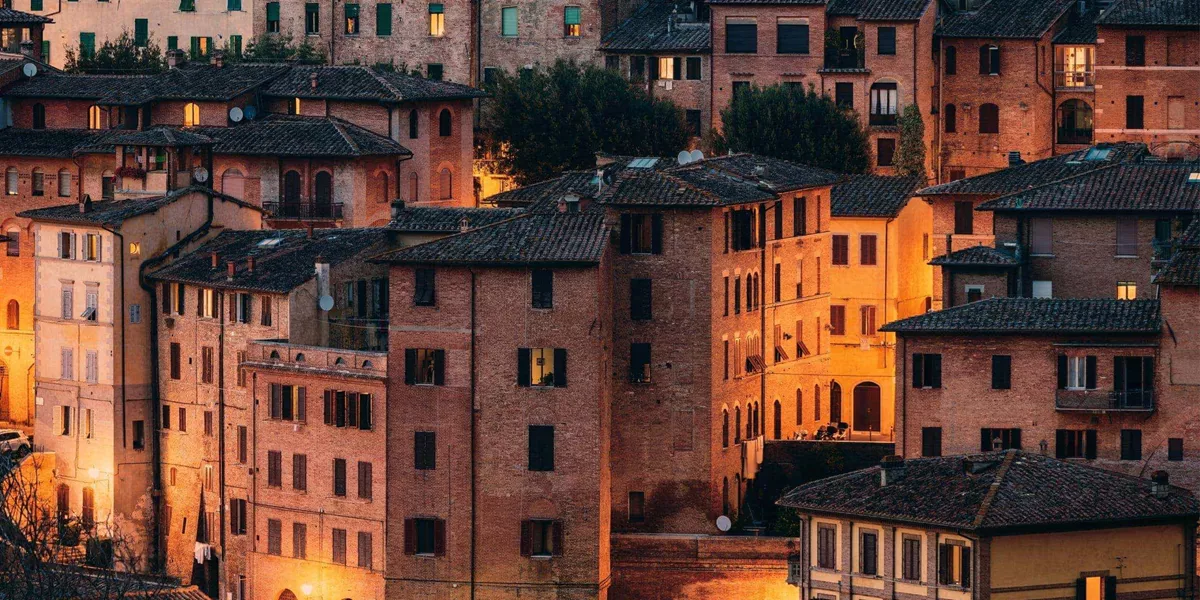 Historic Tuscan town at sunset, featuring terracotta rooftops and traditional Italian architecture on the Contikii Tuscan Escape Tour