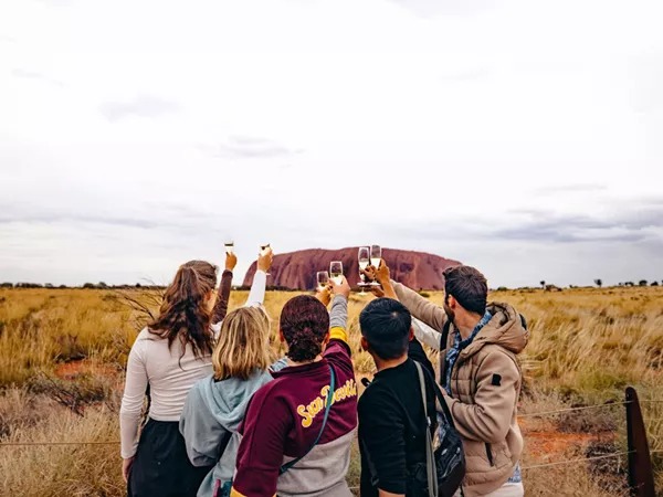 A group of people taking a photo of a large rocky mountain in Australia.