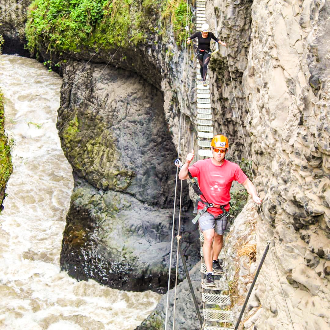 Traveller walking across a wire bridge in Banos, Ecuador