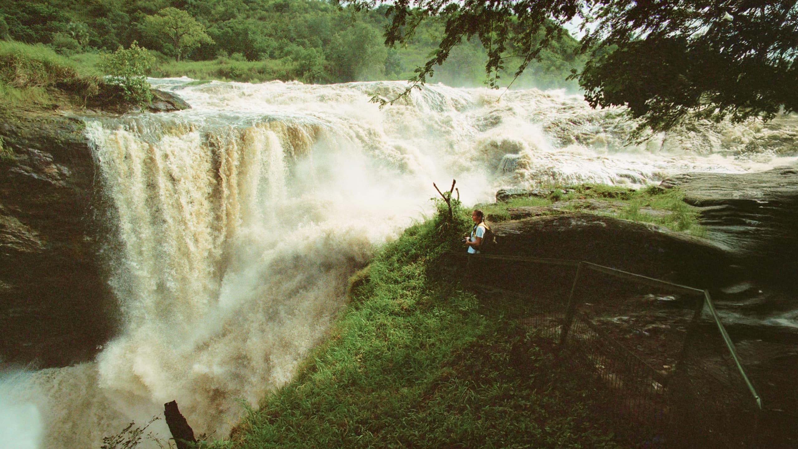 Traveller standing at the viewing platform beside the thundering Murchison Falls on the Victoria Nile in Murchison Falls National Park Uganda - Contiki Uganda Tour