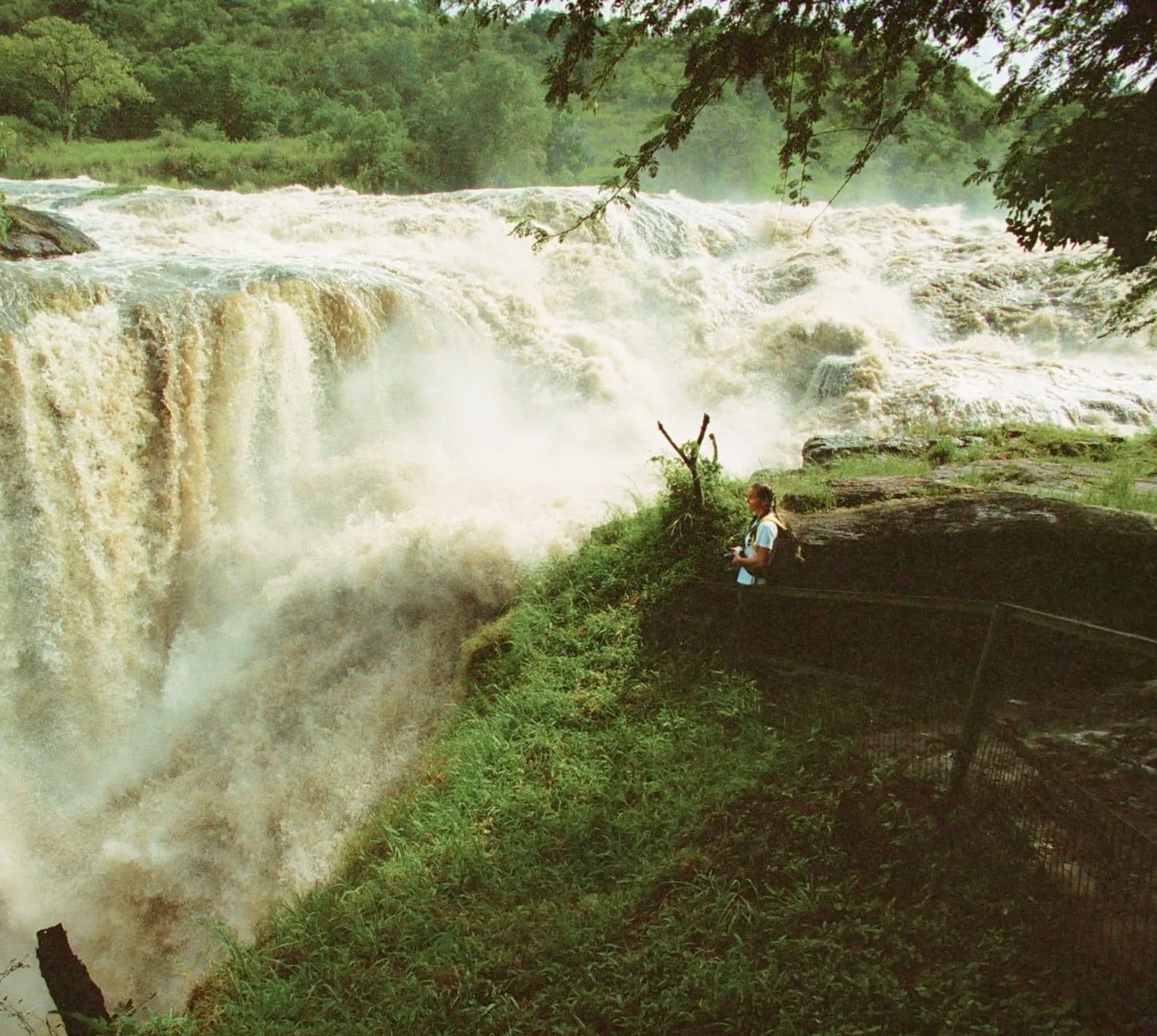 Traveller standing at the viewing platform beside the thundering Murchison Falls on the Victoria Nile in Murchison Falls National Park Uganda - Contiki Uganda Tour